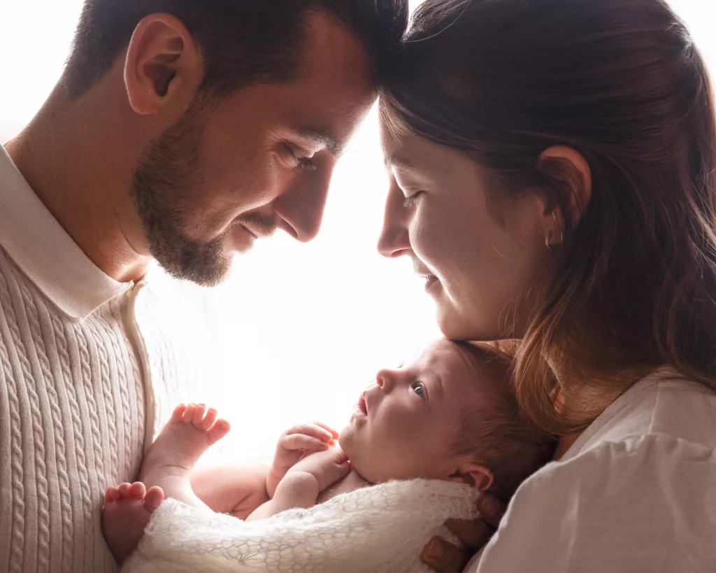 Séance photo naissance au studio à contre jour dans les bras des parents